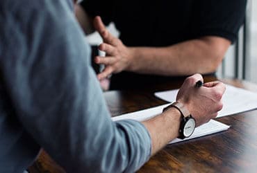 a two men collaborating with pen and notebook
